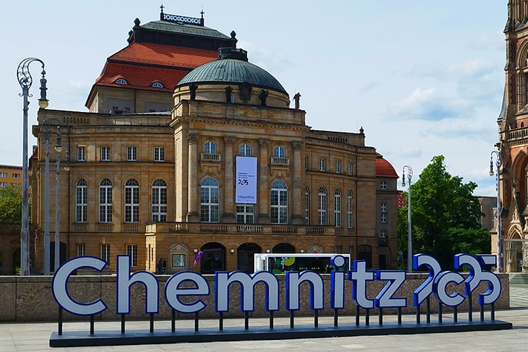 Blick auf das Opernhaus Chemnitz mit großem Schriftzug 'Chemnitz 2025' im Vordergrund – Hinweis auf die Kulturhauptstadt Europas 2025.